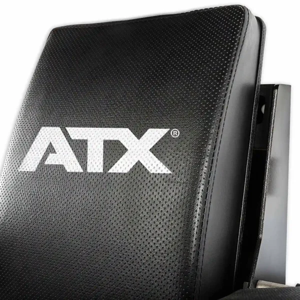 A close-up view of the black leather surface on the ATX® Wall Mounted Knee Raise & Dip, showcasing the prominently printed white ATX logo. The leather features a perforated texture with visible stitching detail along the edges.