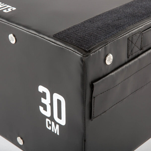 The ATX® 30 cm Soft Drop Block features a close-up of its black surface with reinforced corners and Velcro straps for stability, offering a durable option for workouts.