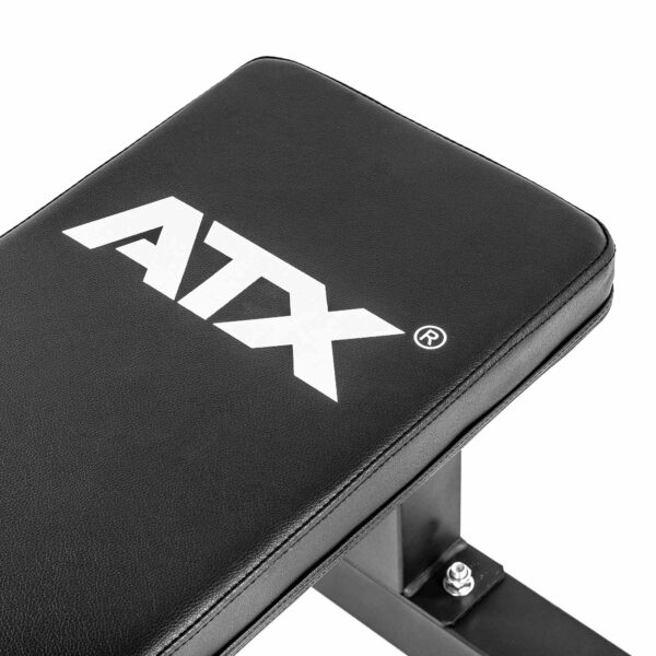 Close-up of a black ATX® Flat Bench PRO with white ATX lettering. The workout bench has a metallic frame and visible bolts.
