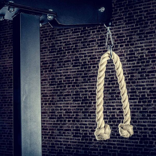 The ATX® V Bar Rotational Blackline, a hanging rope exercise attachment with metal clips, is displayed against a textured brick wall, ideal for strength training equipment.