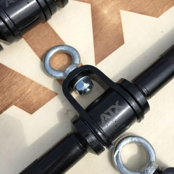 Close-up of a black metal rod marked ATX®, showing two metal eye bolts and a U-shaped bracket with a nut. The ATX® EZ Curl Rotational Blackline rests on a brown and white geometric patterned surface.