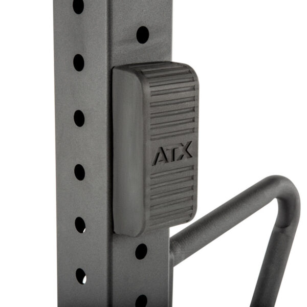Close-up of an ATX® Jammer Arms adjustable safety stop on a gym rack, featuring a textured handle and multiple holes for height adjustment.