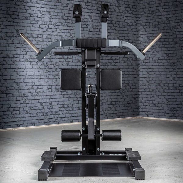 The ATX® Leg Master, a versatile black and gray gym machine on a concrete floor against a gray brick wall, features padded back and arm supports, handles for upper body exercises, and an integrated standing leg curl function for comprehensive arm and leg workouts.