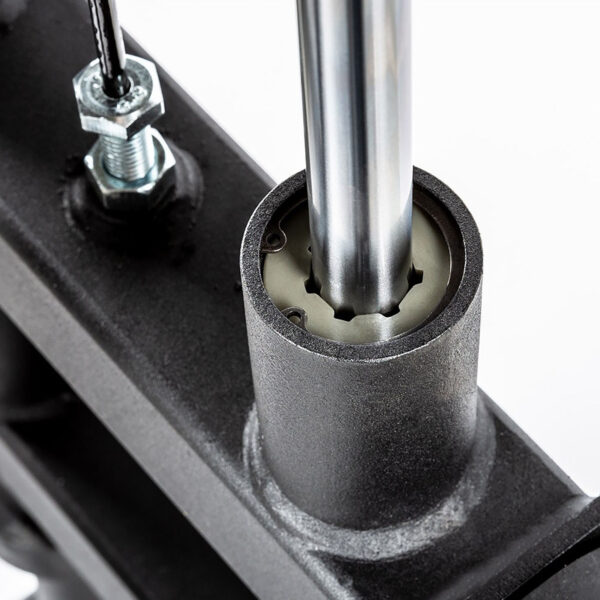 Close-up of a shiny cylindrical metal rod inserted into an ATX® Lat Option 650 Plate Loaded component, with a threaded bolt and wire nearby, contrasting the matte black parts.