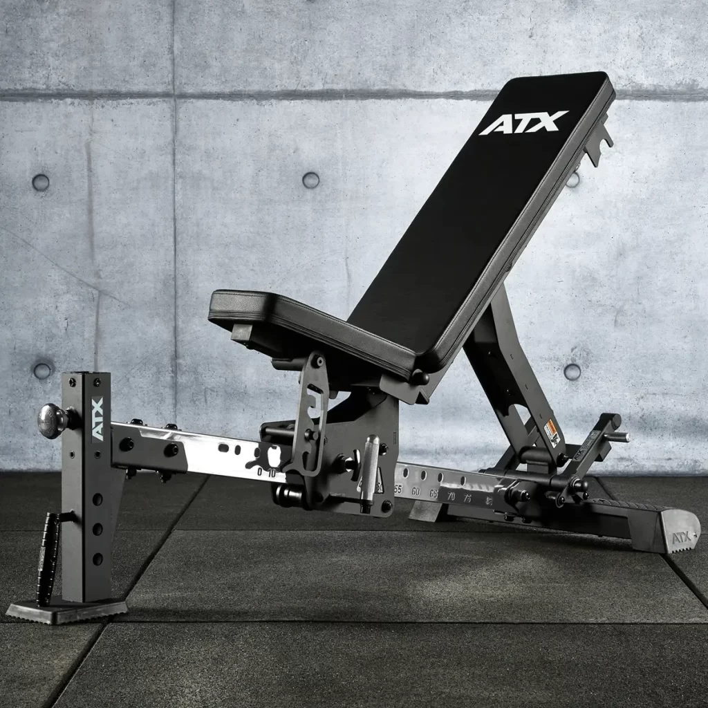 The ATX® Multi Bench is adjustable with a black cushioned seat and backrest featuring the ATX brand, shown in an incline position on a textured mat against a concrete wall.