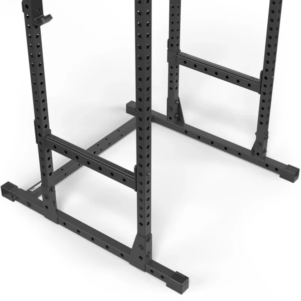 The ATX® Power Rack 520 215cm, made of black metal with adjustable holes, is shown from an angle displaying its base and lower frame on a plain white floor.