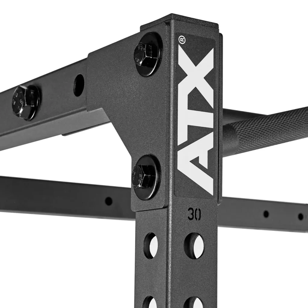Close-up of the ATX® Power Rack 520 215cm, a sturdy black metal gym frame with the ATX logo. It features numbered holes for adjustability, secured by large bolts, and a partially visible knurled pull-up bar.