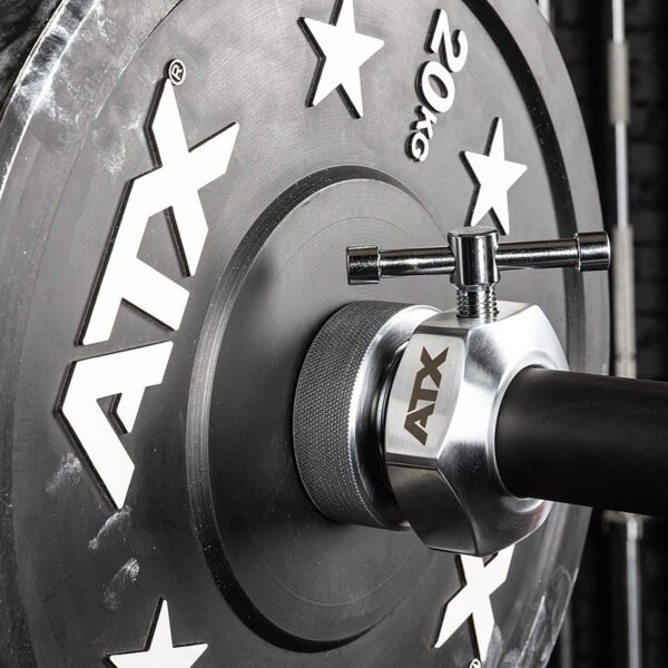 Close-up of a 20 kg weight plate loaded on a barbell, secured with an ATX® Competition Collars Short IPF. The plate displays ATX branding and star designs, with the textured grip area visible on the barbell.