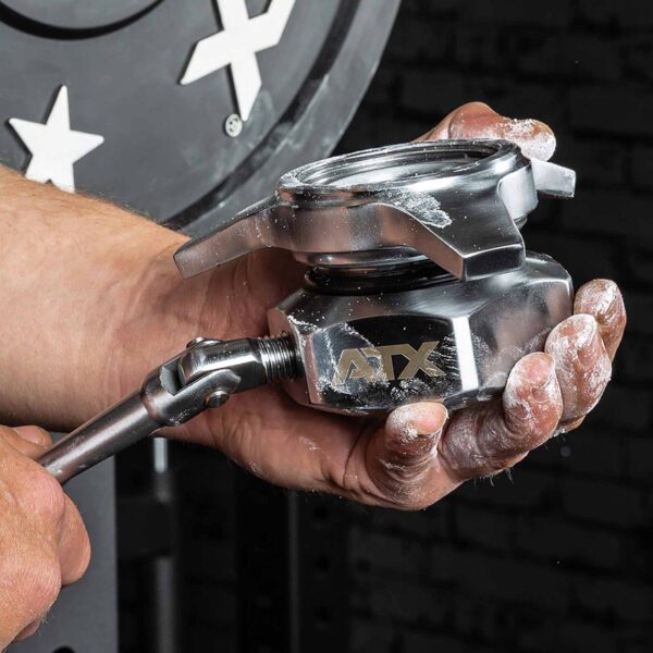 A person holds a shiny ATX® Competition Powerlifting Collar IPF, crucial for securing weightlifting collars. The metallic clamp is chalk-dusted in their hand, with gym equipment subtly blurred in the background.