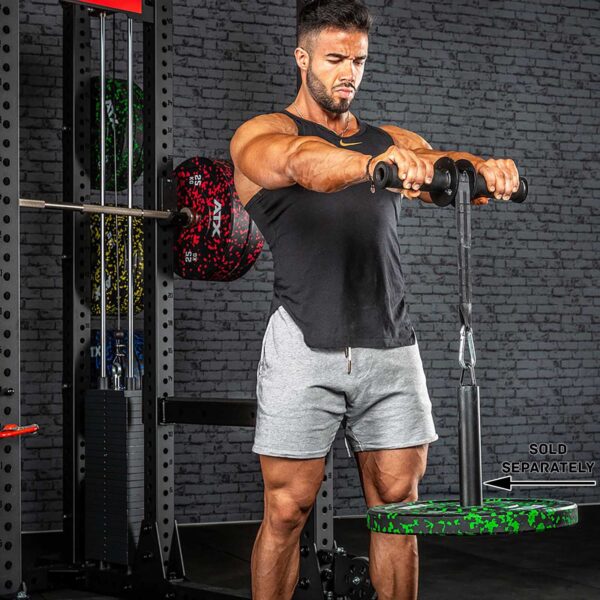 A man in a gym uses an ATX® Wrist Forearm Trainer to lift a weighted plate with a rope. He is wearing a black tank top and gray shorts, standing in front of a wall of gym equipment.