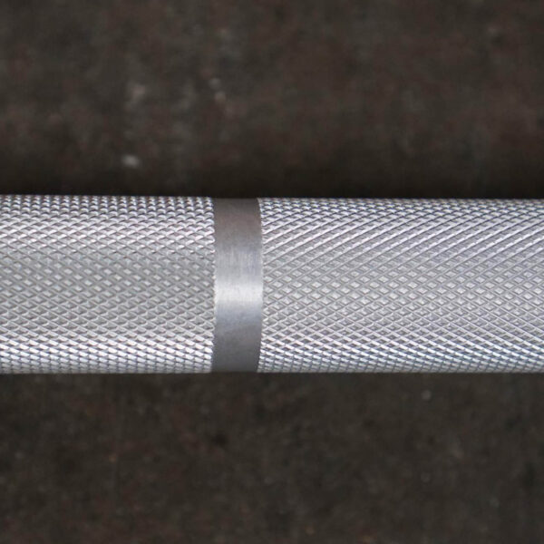 Close-up of the Aluminium 7.5kg Technique Olympic Bar featuring a textured, diamond-patterned grip and a smooth center band, set against a dark background.