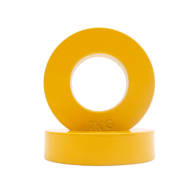Two yellow plates from the Power Maxx Olympic 5kg Fractional Plate Set are stacked; one is upright with 1KG embossed at the bottom, and the other lies flat beneath it.