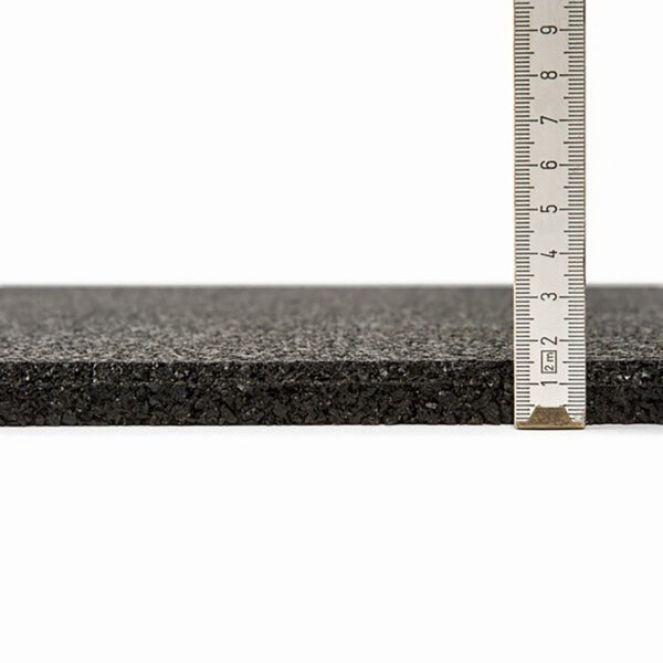 A close-up of the GymFloor® 15mm 1m x 1m Black slab features a ruler on the right side, showcasing its approximate thickness of 1.5 centimeters with a textured surface.