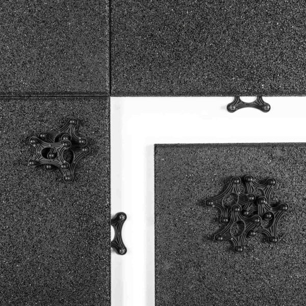 A symmetrical pattern on black Gymfloor® 20mm tiles with three abstract star shapes, crossed diagonally by a white strip dividing the tile sections.