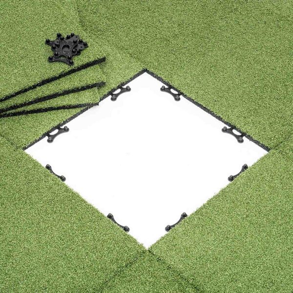 A section of GymFloor® RTS Turf 50x50@20mm is removed to expose a white square base. Nearby, black connectors and rods on the grass indicate upcoming assembly or installation.