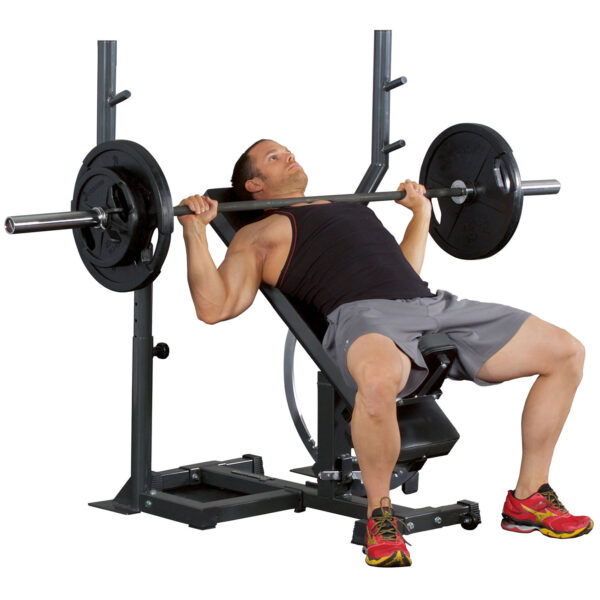 Wearing a black tank top and gray shorts, an individual uses the Ironmaster Barbell Attachment to perform an incline bench press in the gym. Theyre positioned on the inclined bench with the exercise rack visible behind them.