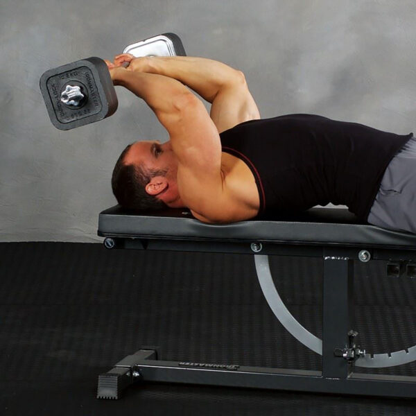 Lying on a bench, someone uses an Ironmaster EZ Curl Bar for a tricep extension. Theyre in a black tank top and gray shorts, extending their arms overhead. The background features a gray wall and black floor mat.