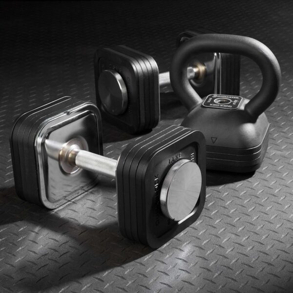 A set of adjustable dumbbells with black square plates and the Ironmaster Adjustable Kettlebell Handle rests on a textured rubber gym floor. The equipment features a modern design, ideal for strength training exercises.