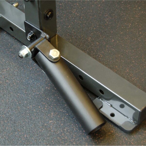 The Ironmaster Landmine Attachment, in black metal, is securely attached to a gym rack on a dark speckled floor. This versatile sleeve device enhances barbell exercises for dynamic strength routines.
