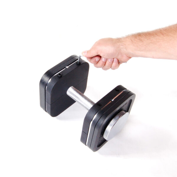 A hand is adjusting weights on an Ironmaster Heavy Handle Kit placed on a white surface. The dumbbell has square weight plates and a metallic handle, offering versatile strength training options.