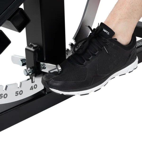 A person wearing a black and white athletic shoe is positioned on a gear-like mechanism marked with measurements, likely part of an Ironmaster Super Bench PRO exercise bench.