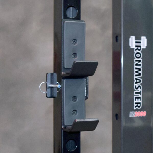 Close-up of an Ironmaster IM2000 J-Hooks weightlifting rack in black with adjustable safety catches featuring a pin lock, and the logo is visible on the right side.