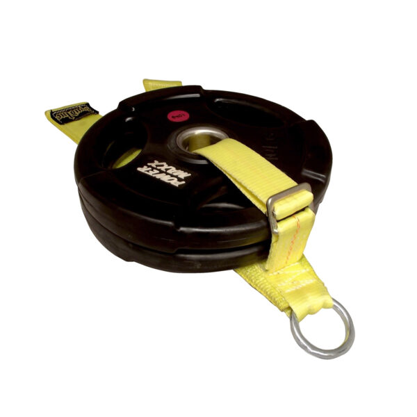 The Spud Inc Cheap Bastard Sled features a black weight plate attached to a yellow strap looped through the plates holes, with a metal ring at the end for easy attachment, ideal for resistance or strength training.