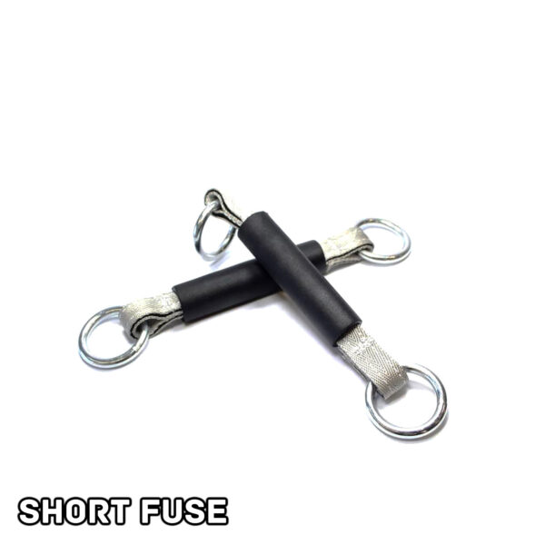 Two black and silver Spud Inc Dynamite Stick resistance bands with metal rings at each end are crossed on a white background. SHORT FUSE is printed in bold black letters in the bottom left corner.