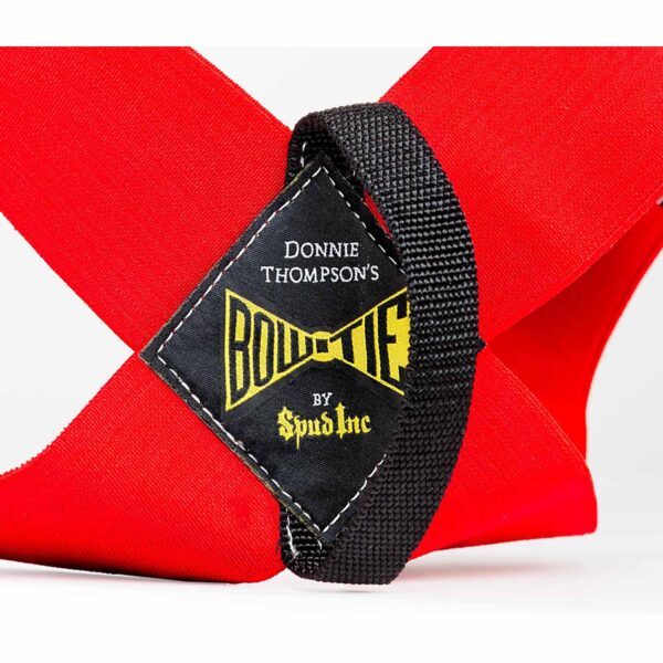 Close-up of a red lifting strap crossing a black strap with a patch label that reads Spud Inc Bowtie Casual in yellow and white lettering.