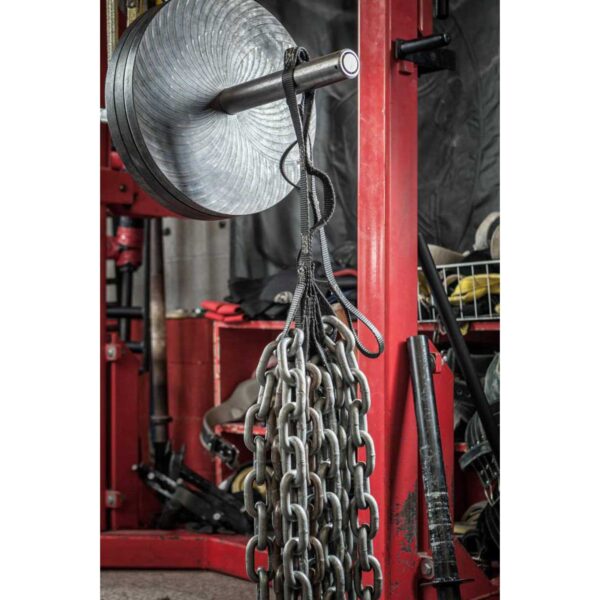 A gym setup featuring a red power rack with weight plates on a bar, heavy chains hanging from it, and Spud Looper Straps visible among accessories and equipment in the background.