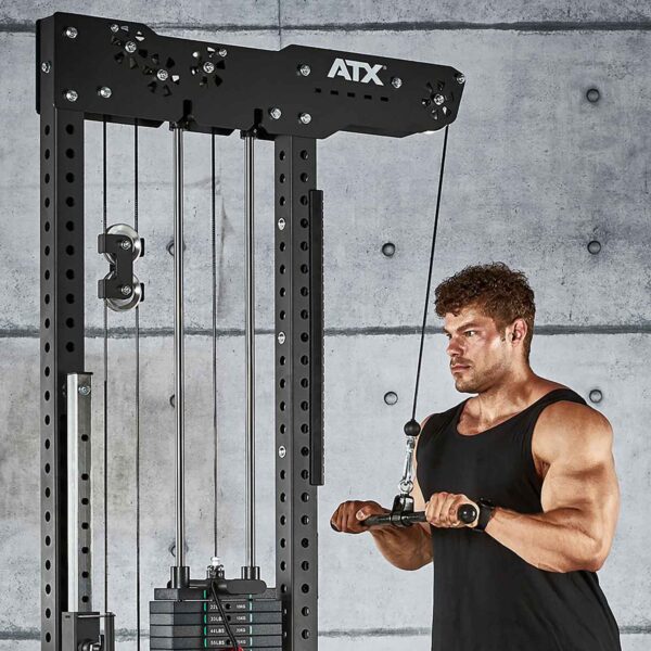 Wearing a sleeveless black top and a focused expression, someone uses the ATX® Straight Bar Rotational Blackline for tricep pushdowns in the gym, set against a gray concrete wall backdrop.