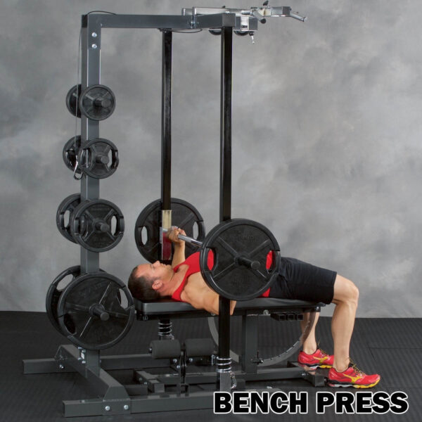 A person in a red tank top uses the Ironmaster IM2000 Self-Spotting Smith Machine for a bench press with a barbell and weight plates. The text BENCH PRESS appears in the bottom right corner.