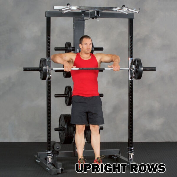 A person in a red tank top and black shorts does upright rows in a gym using the Ironmaster IM2000 Self-Spotting Smith Machine, lifting the barbell to chest height. Text reads, UPRIGHT ROWS.