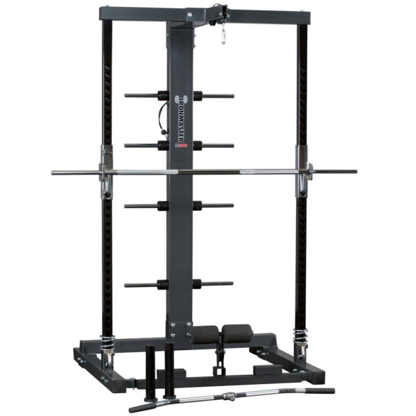 The Ironmaster IM2000 Self-Spotting Smith Machine features adjustable safety bars, a pull-up bar, and multiple weight plate holders. A barbell rests on the safety hooks, with attachments like a curl bar and handle lying before it.
