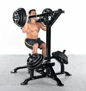 A person performs a shoulder press with a weight machine, seated and holding bars with weights. They wear black shorts with yellow stripes. Several additional weights rest on the machine base.