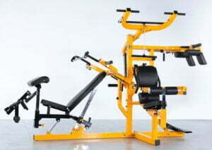 A multi-station home gym with a yellow frame and black cushioning against a plain background. It features an adjustable bench, pulleys, and various attachments for strength training exercises.