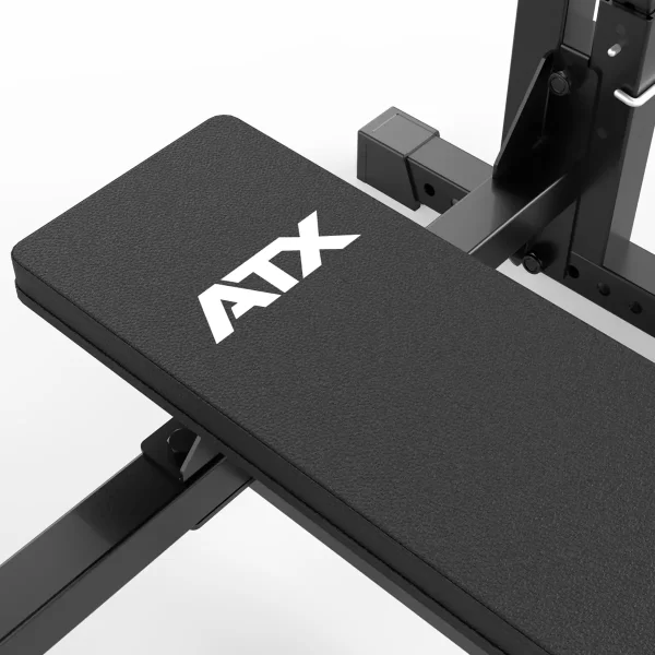 Close-up view of the ATX® Olympic Bench Press 700, a black gym bench with ATX on the padded surface, featuring adjustable metal components and a sturdy frame.