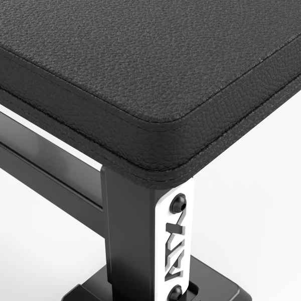 Close-up of the ATX® Olympic Bench Press 700, showcasing a black textured corner with part of the metal frame and bolt details. The durable upholstery highlights its design for gym equipment.