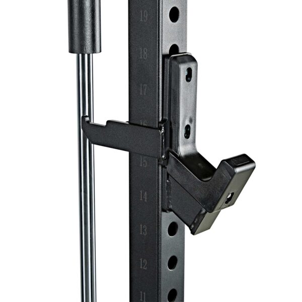 Close-up of the ATX® Smith Machine System Stack Weight 115 kg, featuring a numbered height adjustment system and a black metal safety hook attached for barbell support. Vertical silver bars are visible near the adjuster.