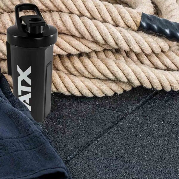 Resting on the GymFloor RTS 50x50@20mm System are a black shaker bottle featuring AVA lettering and coiled battle ropes, with a dark towel partially visible in the foreground.