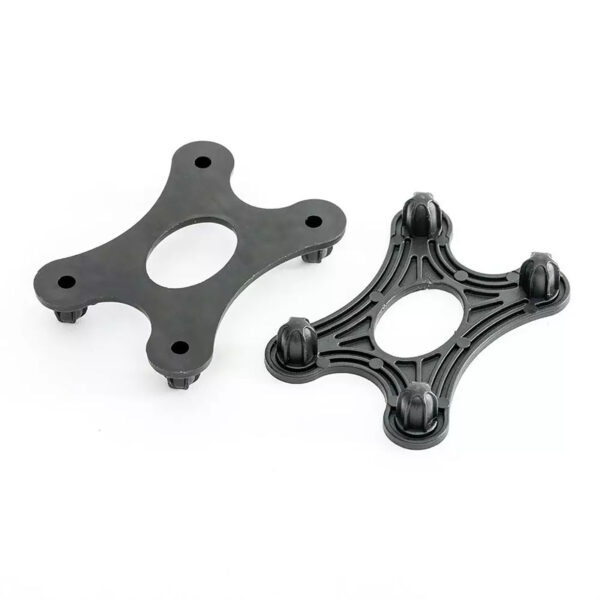 Two black plastic spider strainer connectors with four prongs and a central oval opening from the GymFloor RTS 50x50@20mm System are displayed. One shows the top view, while the other displays the underside with prongs visible against a white background.