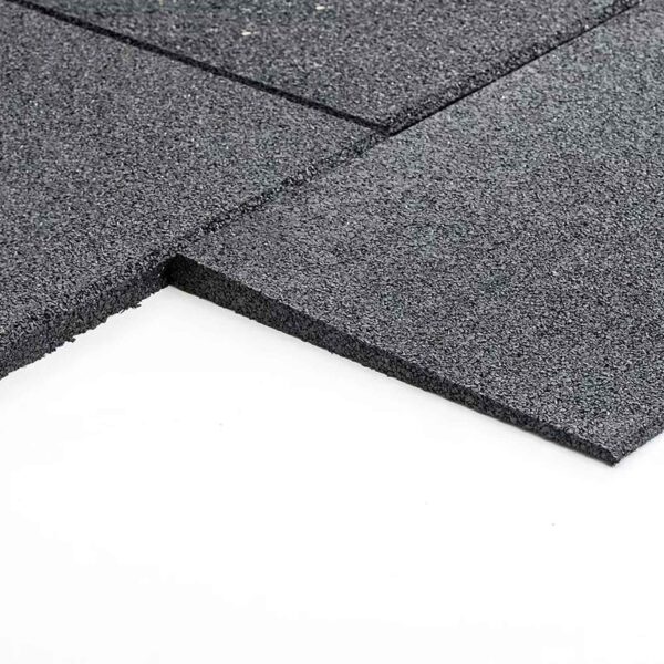 Close-up of GymFloor RTS 50x50@20mm System, featuring square black rubber tiles with a textured, granulated surface, arranged on a white background and slightly stacked to display their thickness.