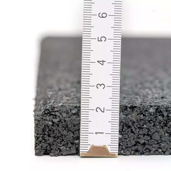 A close-up of the GymFloor RTS 50x50@20mm System on a white background, featuring a black, textured rubber mat. A ruler measures its thickness, highlighting the mats approximately two-centimeter depth.