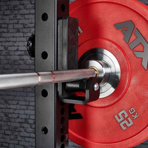 A close-up of a red 25 kg ATX weight plate on a barbell in black ATX® Roller J-Hooks Universal, featuring a textured metal grip with a brick wall backdrop.