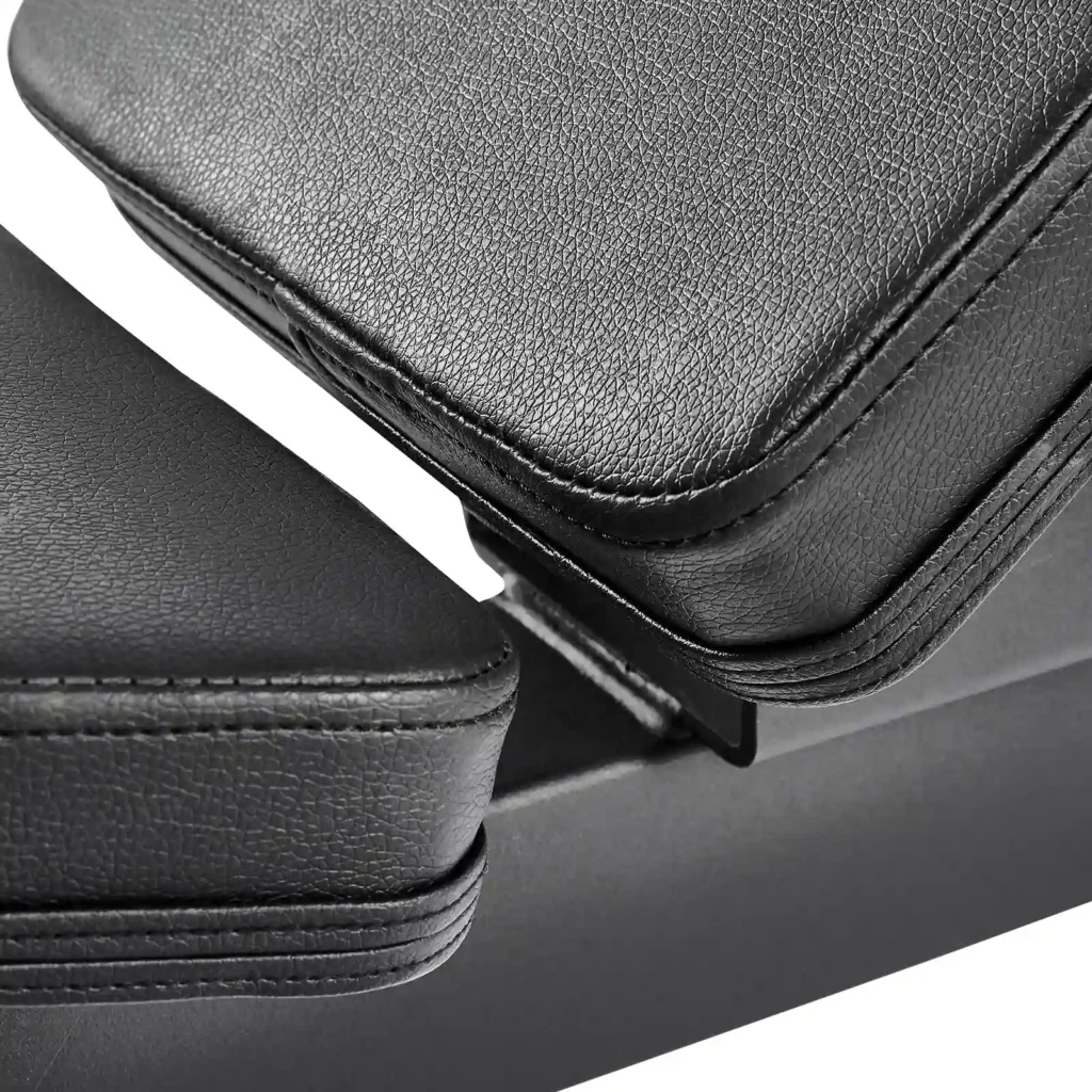 Close-up of a black leather armrest with visible stitching, showcasing its texture and design detail. The image highlights the joining section between two parts of the folding fitness bench against a white background.