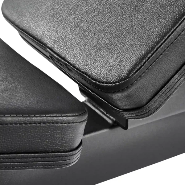 Close-up of a black leather armrest with visible stitching, showcasing its texture and design detail. The image highlights the joining section between two parts of the folding fitness bench against a white background.