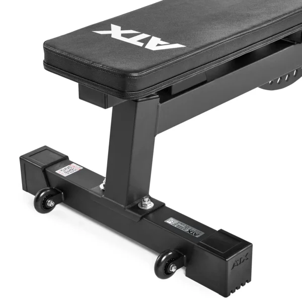 Close-up of a black folding ATX fitness bench with wheels. The cushioned top sits on a sturdy metal frame, ensuring durability and easy mobility. Logos adorn the bench and metal frame, combining functionality with style in your workout space.