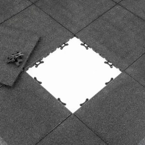 View of Shock & Sound Tile 30mm System in dark gray, with one tile partially removed to reveal a white surface underneath. A corner piece lies on the side, highlighting the tiles textured surface and connector designs.