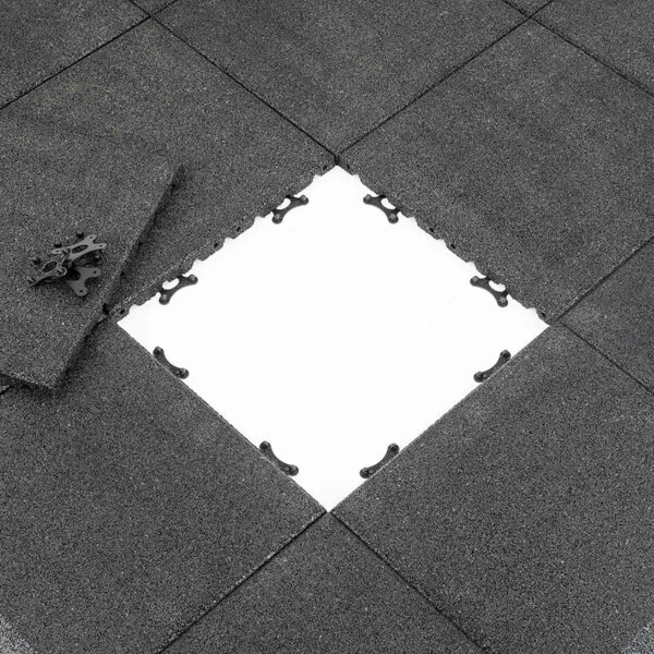View of Shock & Sound Tile 30mm System in dark gray, with one tile partially removed to reveal a white surface underneath. A corner piece lies on the side, highlighting the tiles textured surface and connector designs.