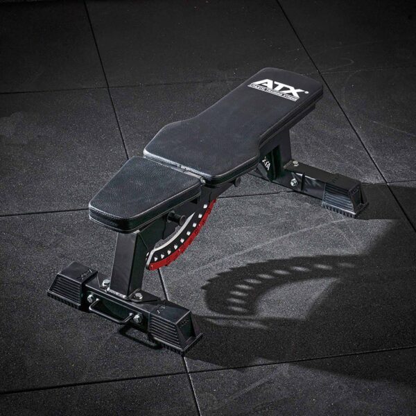 The ATX® Utility Bulls Bench, featuring a padded seat and red adjustment dial, is placed on a dark gym floor. The brand ATX is visible on the backrest.